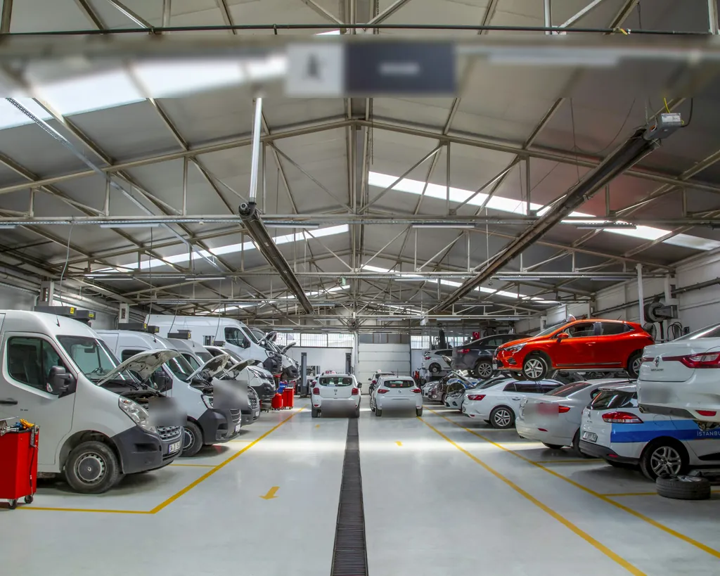 A bright, clean auto service bay with vans and cars on the lifts.